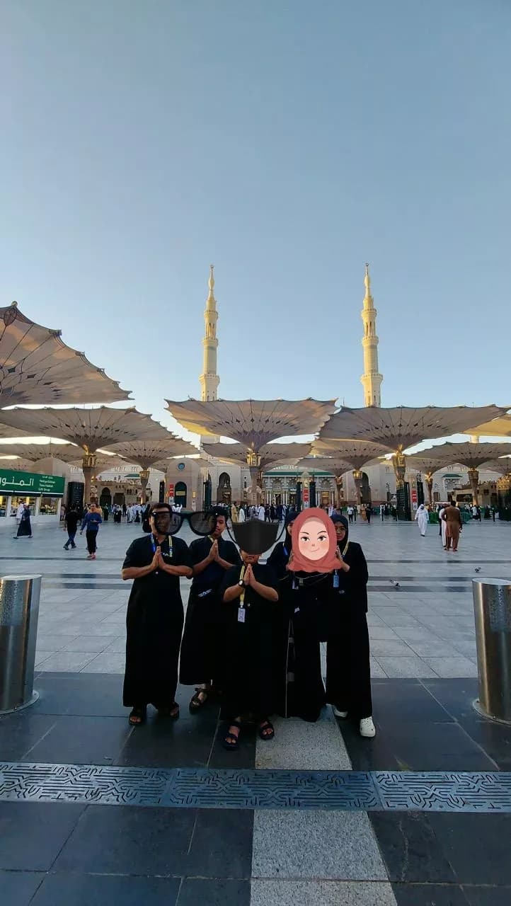 Group posing in the courtyard of Al-Masjid an-Nabawi in Medina under large white umbrellas.